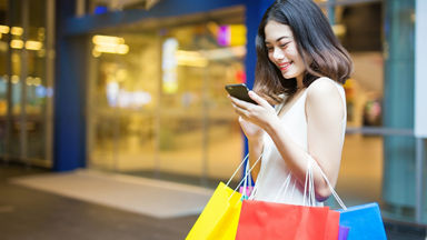 Female on her smartphone with shopping bags on her arms